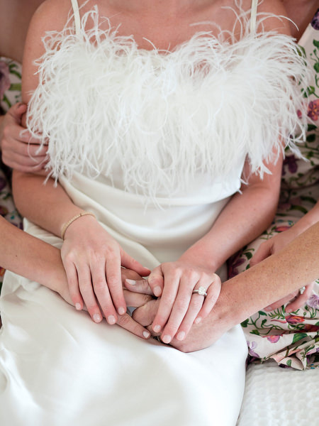 Close-up of bride’s feather wedding dress and engagement ring at Paros destination wedding.