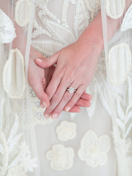 Close-up of bride’s engagement ring against lace wedding dress in Paros Greece.