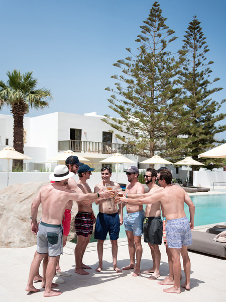 Groom and groomsmen celebrating by pool at Petra Farm Paros wedding.