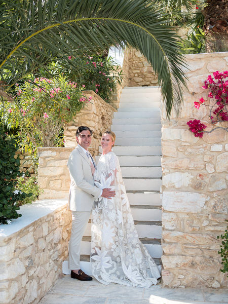 Bride and groom posing on stone steps with bougainvillea at Petra Farm Paros wedding.