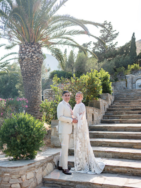 Bride and groom posing on stone steps at Petra Farm chapel wedding in Paros Greece.