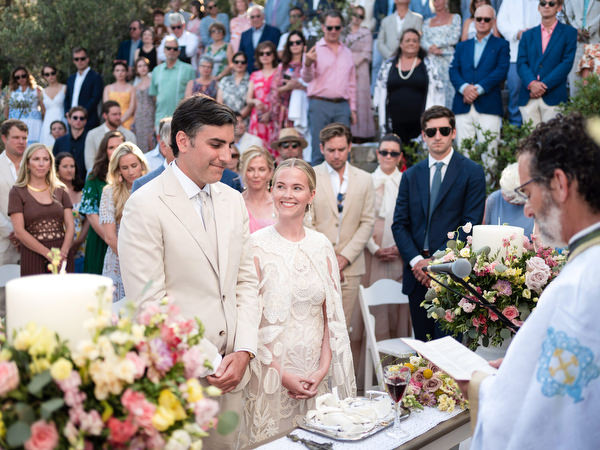 Bride and groom standing before priest during Orthodox wedding at Petra Farm Paros.