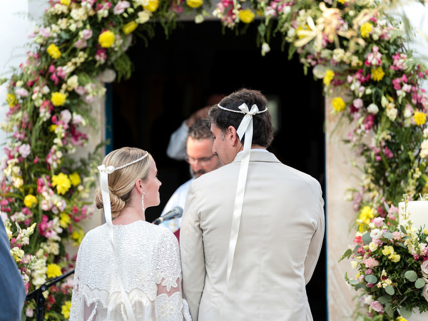 Bride and groom wearing Orthodox wedding crowns at Paros Greek island ceremony.