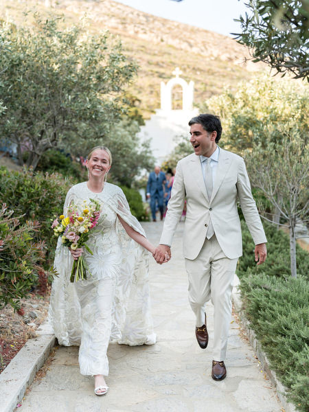 Bride and groom walking through garden path at Petra Farm Paros wedding venue.