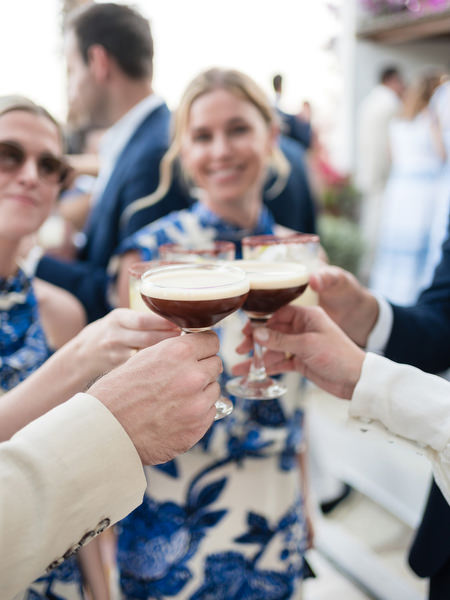 Wedding guests toasting with cocktails during Paros island wedding reception.