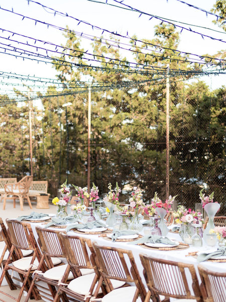 Outdoor Paros wedding reception setup with string lights and floral arrangements.