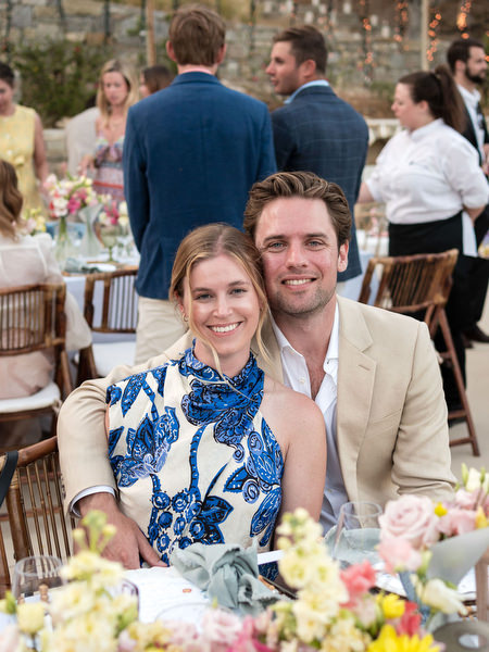 Wedding guests seated at floral reception table during Paros island wedding.