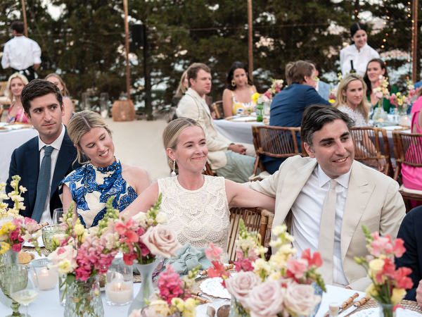 Bride and groom seated at floral head table during sunset reception at Petra Farm Paros.