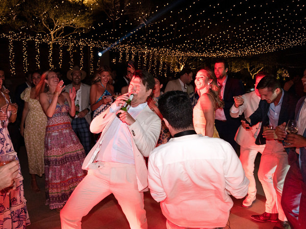 Guests dancing under string lights at Petra Farm Paros wedding party.