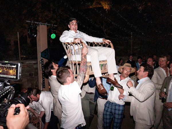 Groom lifted by friends during Paros island wedding reception.