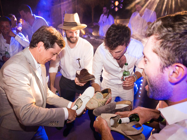 Groom and friends laughing during wedding shoe game at Petra Farm Paros night reception.