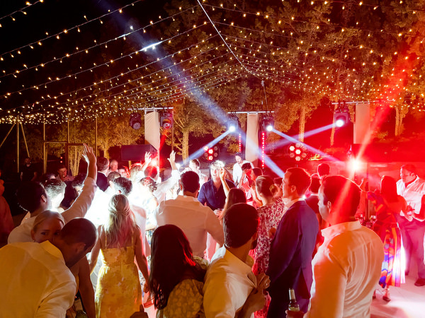 Guests dancing under string lights at Petra Farm Paros wedding party at night.