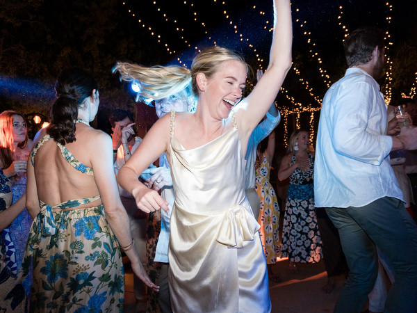 Bride dancing energetically during Paros island wedding party at Petra Farm.