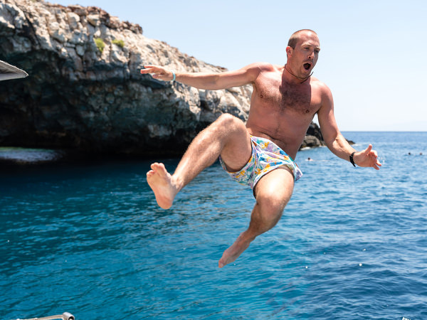 Guest jumping into the sea during Greek island wedding boat trip