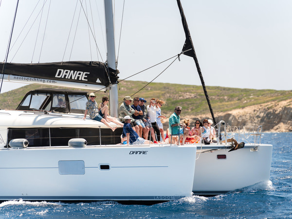 Catamaran anchored near rocky cliffs in Paros swimming spot