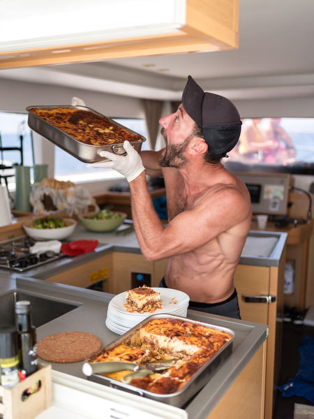 Captain serving pastitsio on sailing boat during Paros celebration