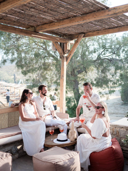 Guests relaxing under beach bar pergola during Paros wedding welcome