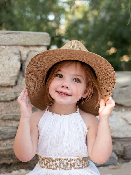 Child wearing straw hat during Greek island wedding event