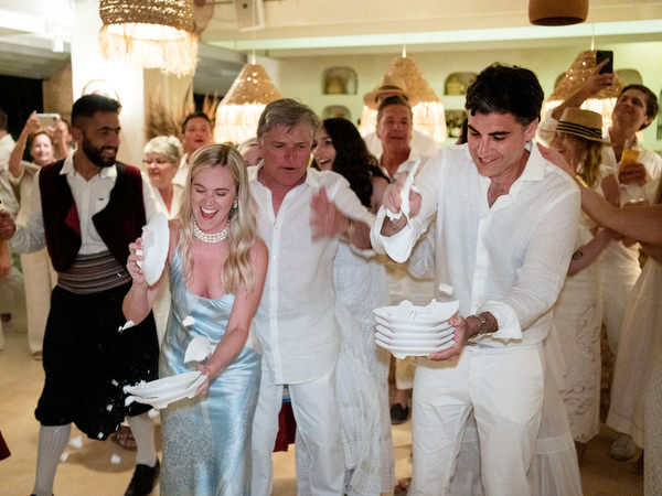 Bride and groom celebrating and smashing plates during wedding party in Paros