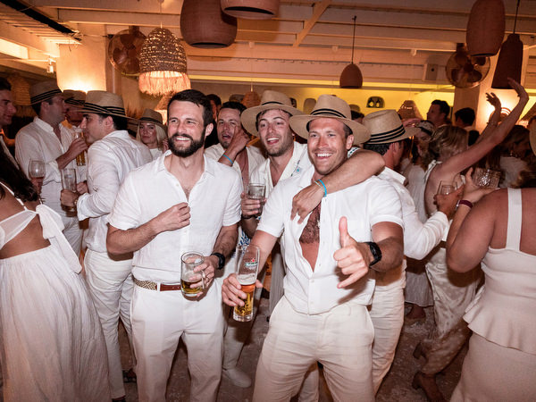 Friends in white dancing during lively Greek island wedding party
