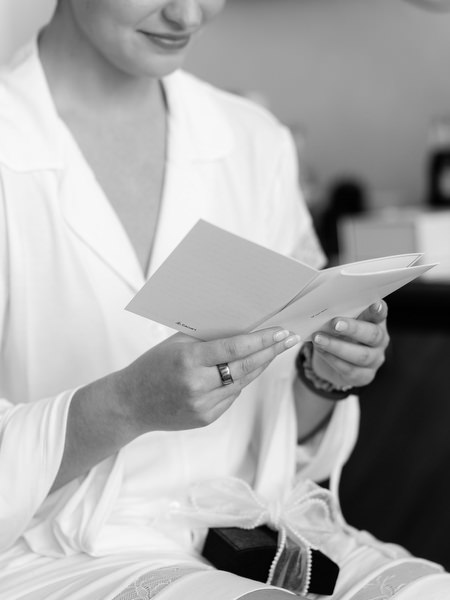 Bride reading handwritten note during luxury Athens wedding preparation before church ceremony.