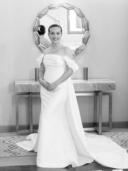 Bride in off-shoulder wedding gown posing indoors before Catholic ceremony in Athens Greece.