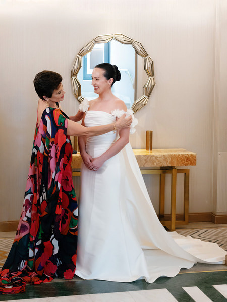 Mother adjusting bride’s gown during preparation for grand Catholic wedding ceremony in Athens.