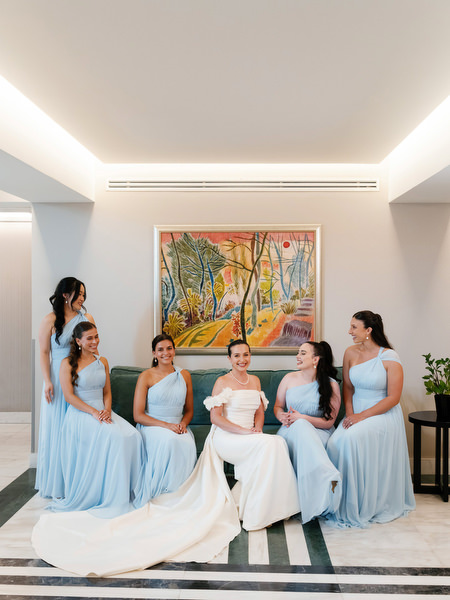 Bride seated with bridesmaids in blue dresses during preparation for Athens destination wedding.