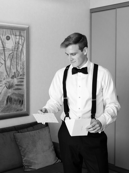 Groom reading handwritten letter during preparation for luxury Catholic wedding in Athens Greece.