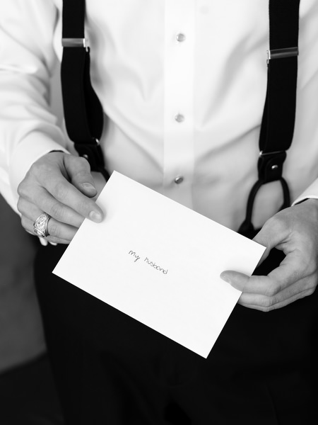 Close-up of groom holding handwritten note before Athens church wedding ceremony.