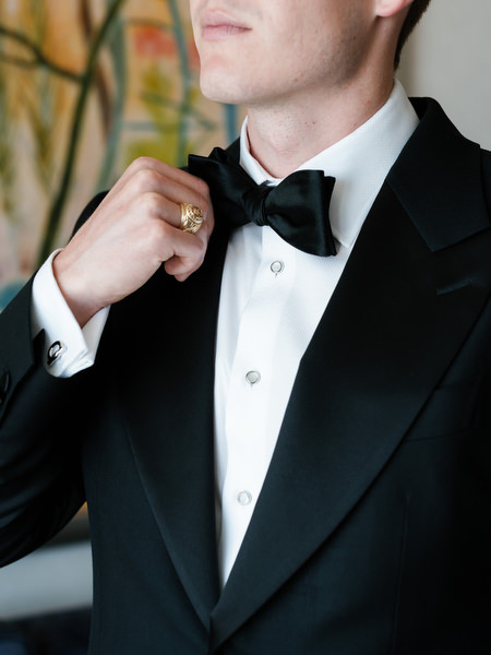 Groom adjusting black bow tie while getting ready for elegant Athens destination wedding.