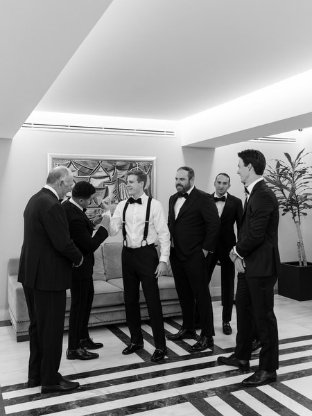 Groom and groomsmen preparing together before grand Catholic church wedding in Athens.
