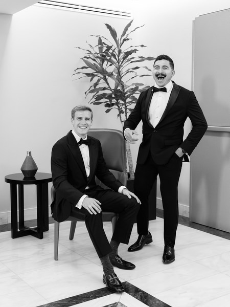 Groom posing with groomsman in tuxedos before Athens luxury church wedding ceremony.