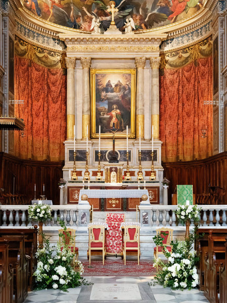 Ornate Catholic church altar decorated with white florals for elegant Athens wedding ceremony.