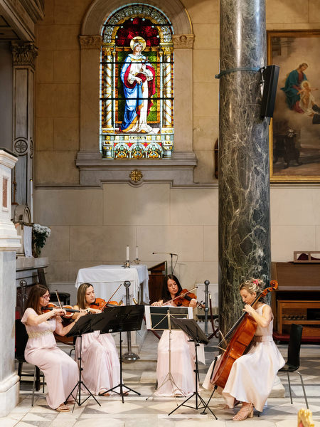 String quartet performing during Catholic wedding ceremony inside grand Athens church.