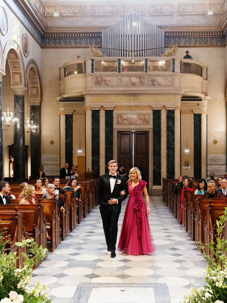 Groom walking down the aisle with his mother inside grand Athens church.