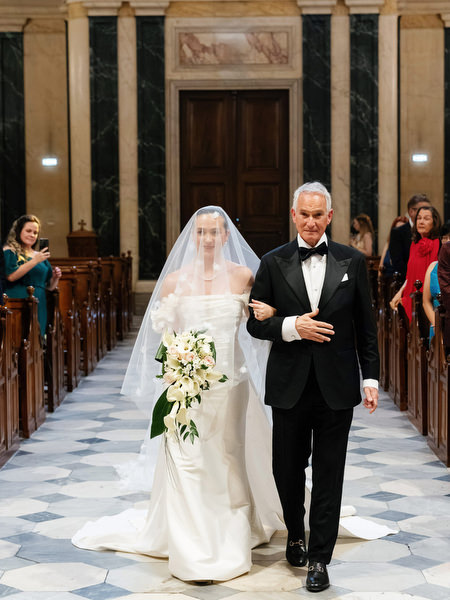 Bride walking down church aisle with her father during luxury Catholic wedding in Athens.