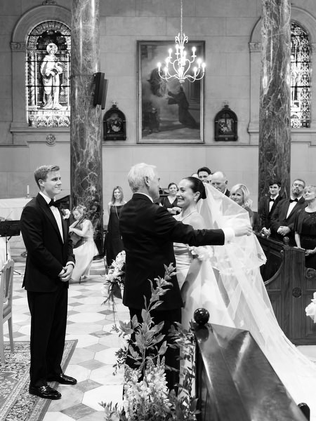 Bride embracing family member at altar during elegant Catholic wedding ceremony in Athens.
