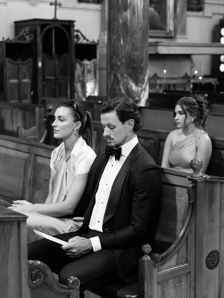 Guests seated in church pew during traditional Catholic wedding ceremony in Athens Greece.