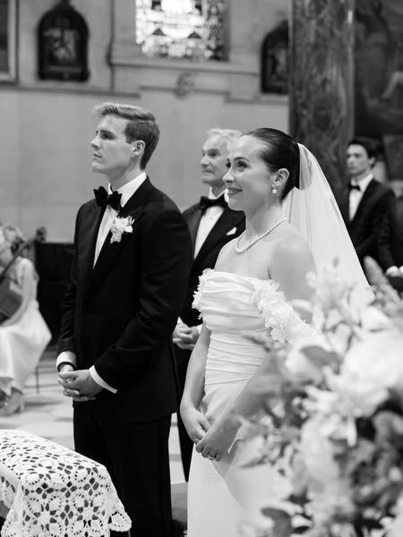 Bride and groom standing together during traditional Catholic wedding ceremony in historic Athens cathedral.