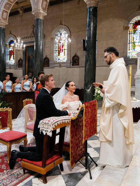 Priest blessing bride and groom during grand Catholic wedding ceremony in Athens Greece.
