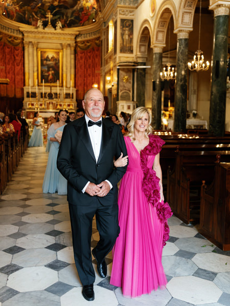 Parents walking down aisle inside Athens Catholic cathedral after wedding ceremony.