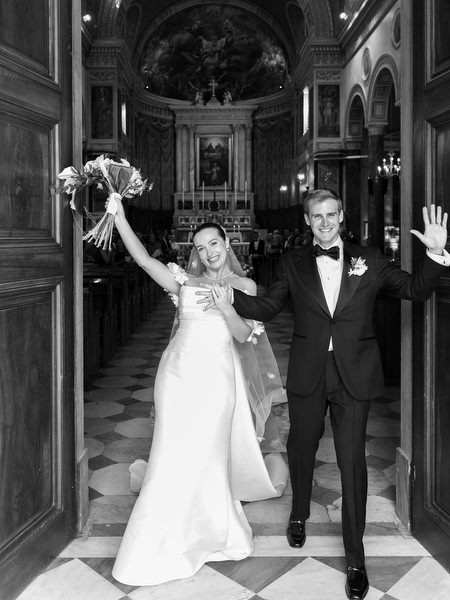 Bride and groom celebrating as they exit Athens Catholic church after ceremony.