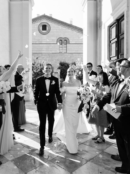 Guests throwing flower petals as bride and groom exit Catholic church in Athens Greece.
