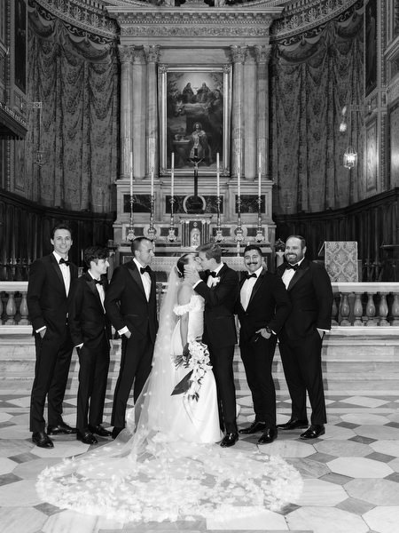 Bride and groom with wedding party inside historic Athens church after Catholic ceremony.