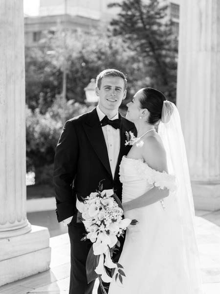 Bride and groom posing under neoclassical arches in Athens after Catholic ceremony before Riviera reception.