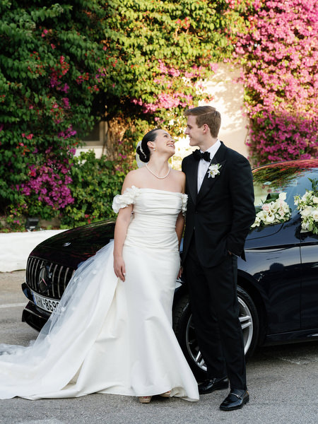 Bride and groom posing at golden hour near luxury car at Island Resort Athens Riviera wedding.