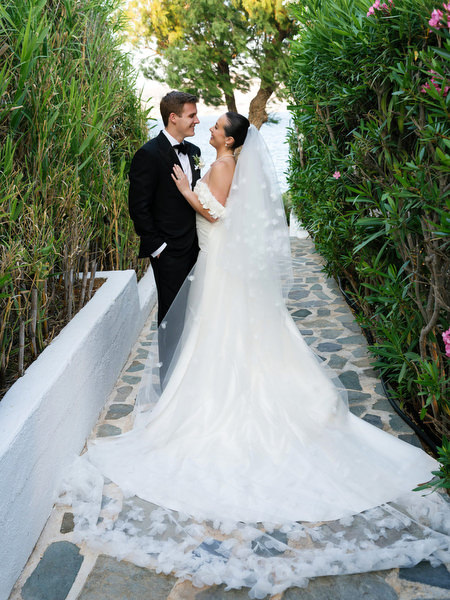 Bride and groom walking along garden path at The Residence Island Resort Athens Riviera during golden hour.