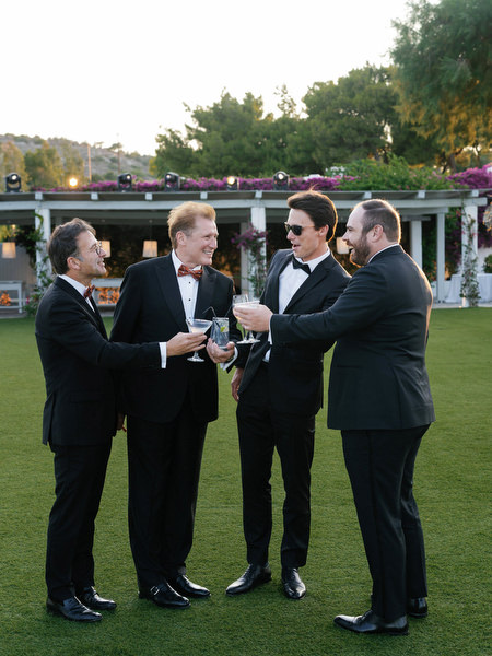 Groomsmen raising cocktails during outdoor reception at The Residence Island Resort Athens.