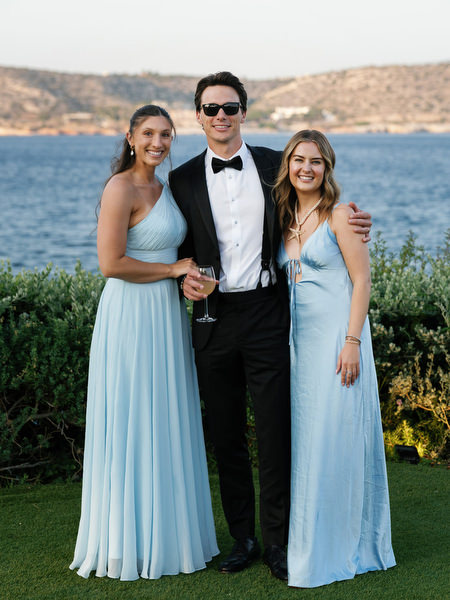 Wedding guests posing by the sea during reception at The Residence Island Resort Athens Riviera.